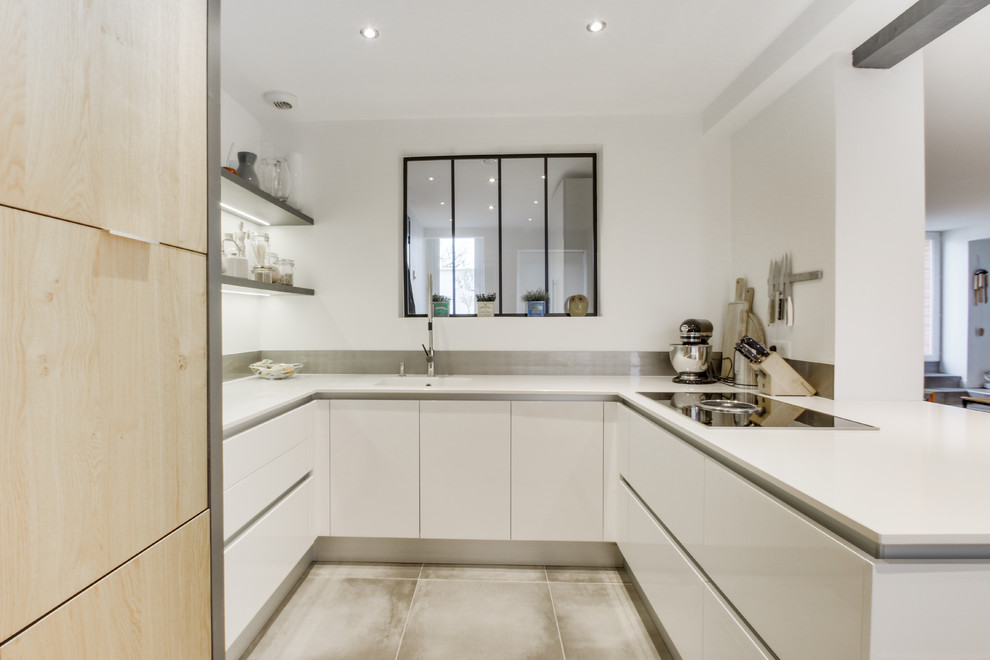 Small scandinavian u-shaped eat-in kitchen in Other with an integrated sink, flat-panel cabinets, white cabinets, quartzite benchtops, grey splashback, glass sheet splashback, panelled appliances, ceramic floors, no island, brown floor and white benchtop.