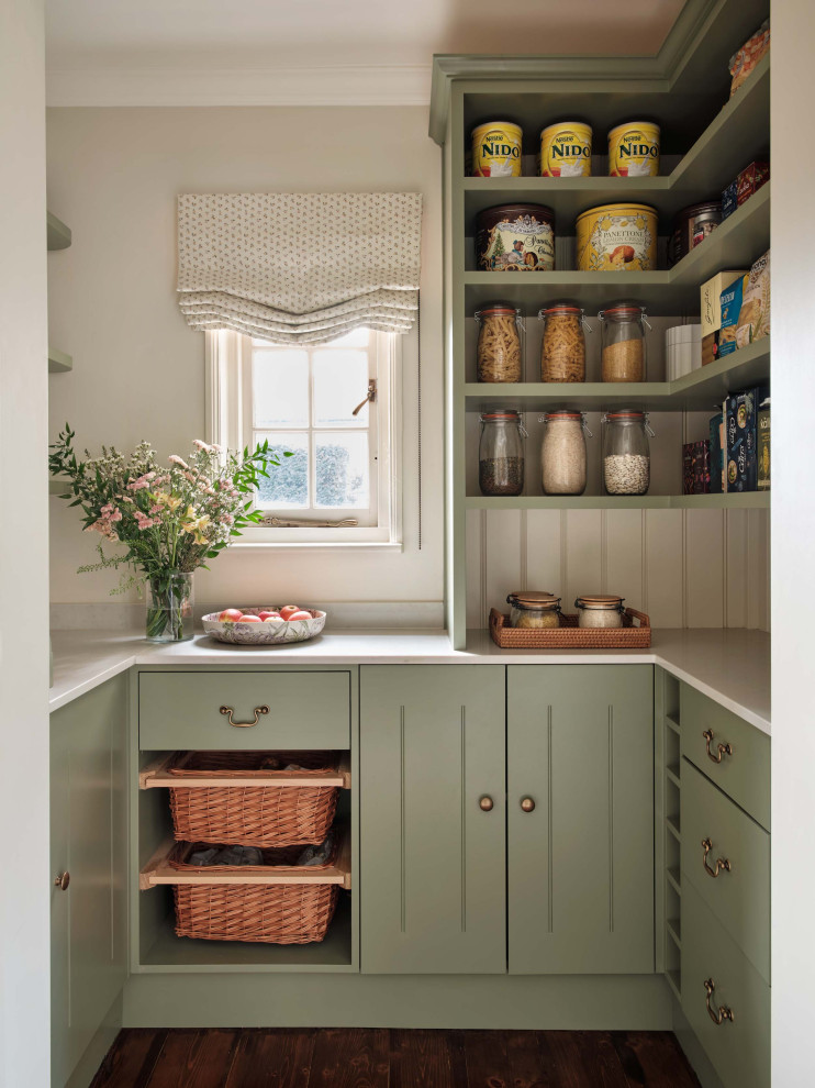 Landhaus Küche in U-Form mit Vorratsschrank, flächenbündigen Schrankfronten, grünen Schränken, dunklem Holzboden, braunem Boden und weißer Arbeitsplatte in Buckinghamshire