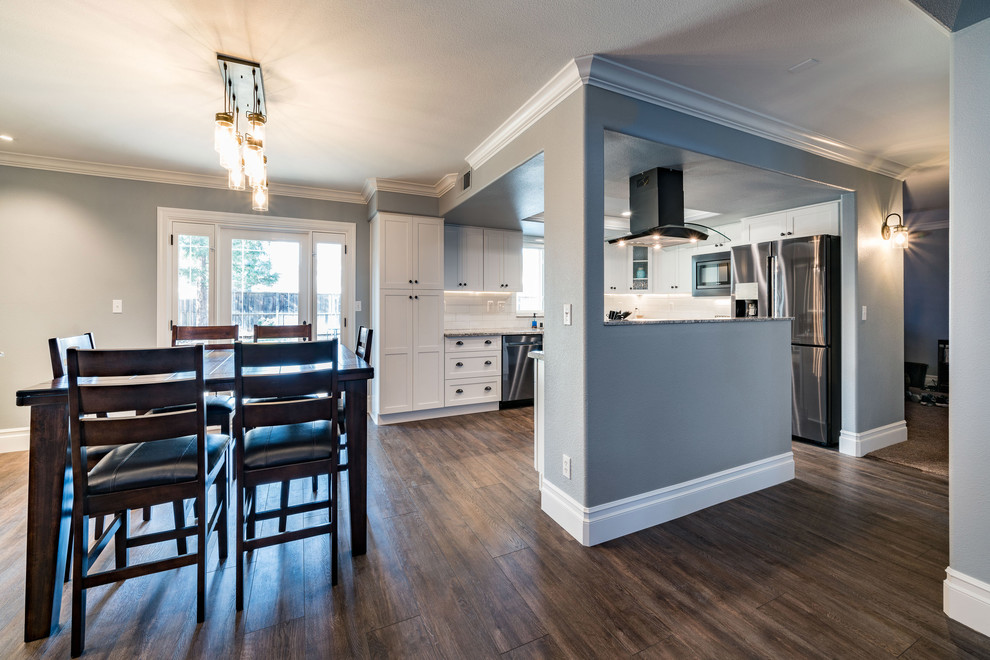 Inspiration for a mid-sized transitional u-shaped dark wood floor and brown floor eat-in kitchen remodel with an undermount sink, shaker cabinets, white cabinets, granite countertops, white backsplash, subway tile backsplash, stainless steel appliances and an island