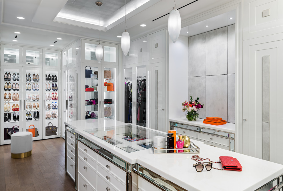 This is an example of a transitional women's dressing room in Toronto with glass-front cabinets, white cabinets and brown floor.