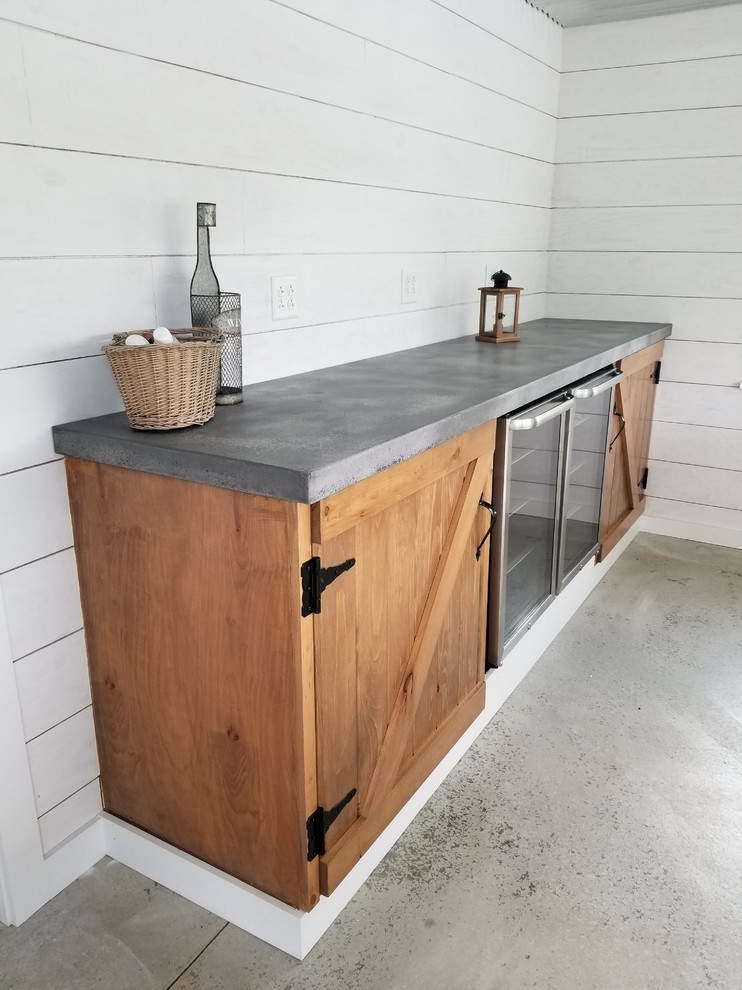 Design ideas for a mid-sized country single-wall home bar in New York with medium wood cabinets, concrete benchtops, concrete floors, grey floor and grey benchtop.
