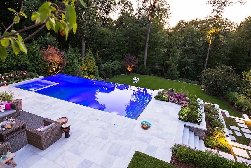 Example of a large backyard stone and custom-shaped hot tub design in New York