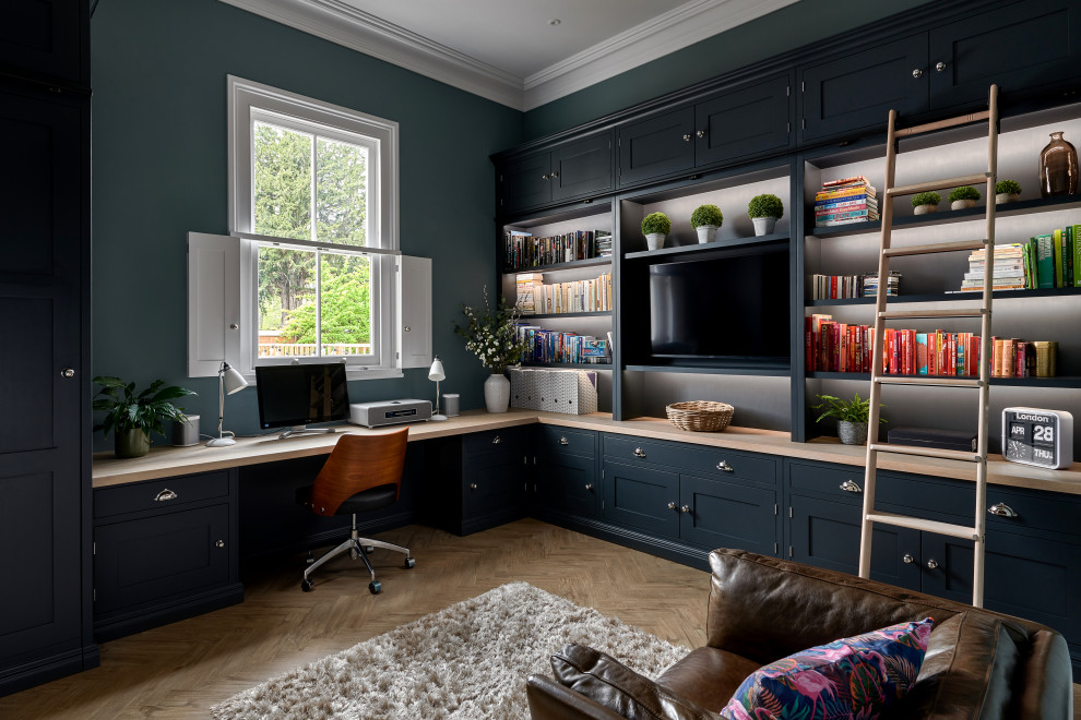 Imagen de despacho abovedado clásico grande sin chimenea con paredes verdes, suelo de madera en tonos medios, escritorio empotrado y suelo marrón