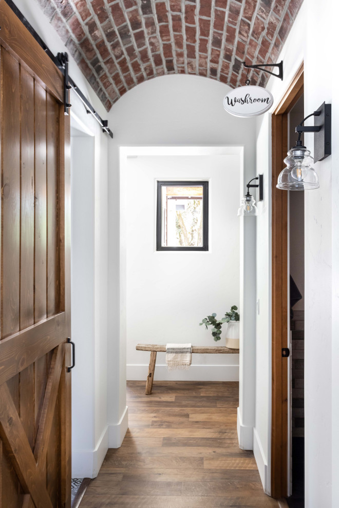 This is an example of a mid-sized country hallway in Sacramento with white walls, vinyl floors, brown floor, coffered and brick walls.