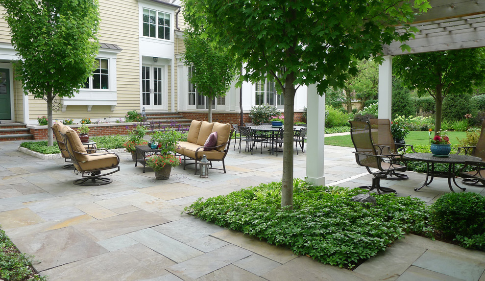 Large country backyard patio in Chicago with natural stone pavers and a pergola.