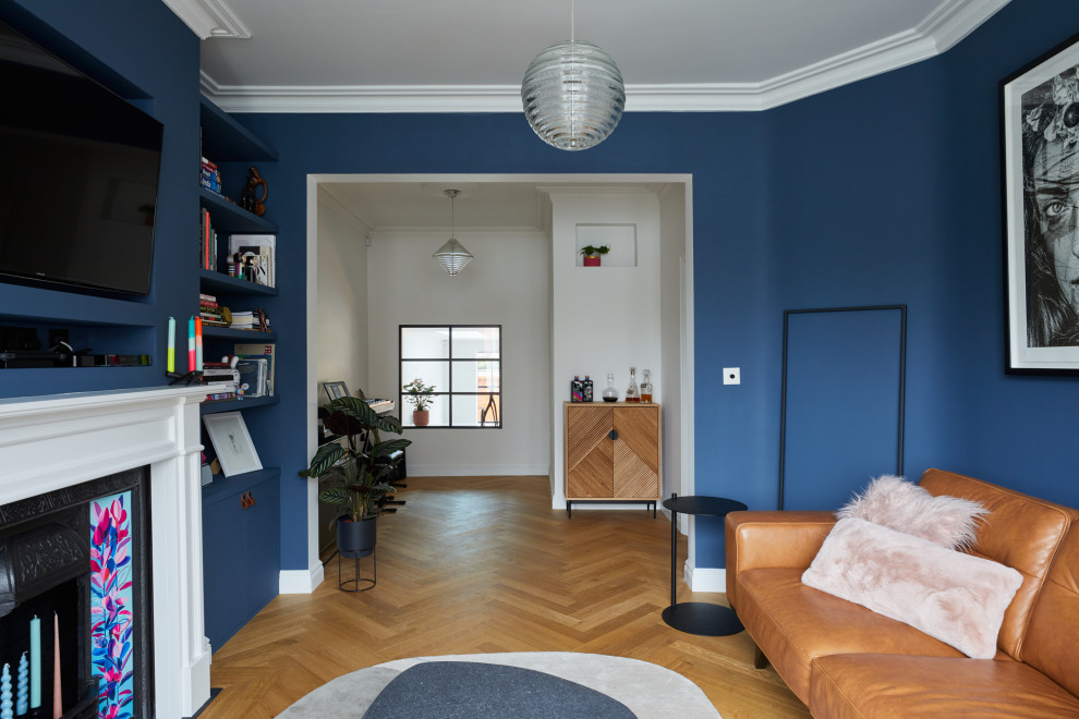 ロンドンにある高級な中くらいなトランジショナルスタイルのおしゃれなLDK (ミュージックルーム、青い壁、淡色無垢フローリング、標準型暖炉、漆喰の暖炉まわり、壁掛け型テレビ、茶色い床) の写真