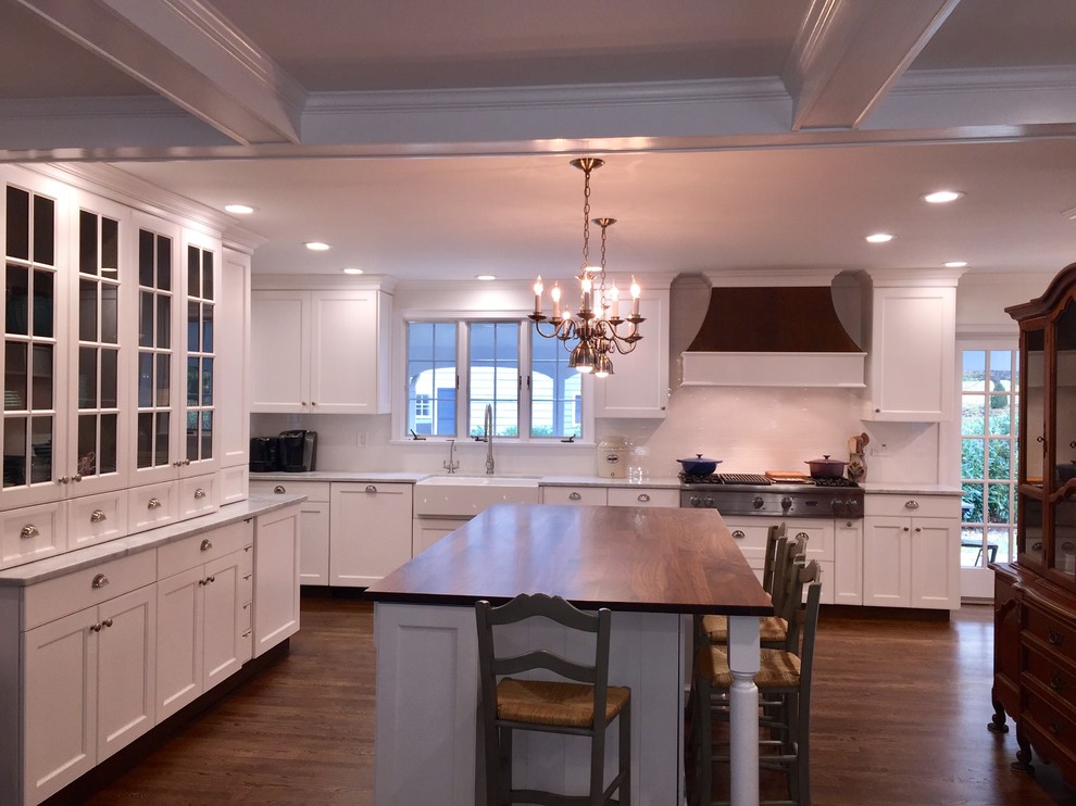 Large traditional l-shaped eat-in kitchen in Philadelphia with a farmhouse sink, shaker cabinets, white cabinets, marble benchtops, white splashback, ceramic splashback, stainless steel appliances, dark hardwood floors and with island.