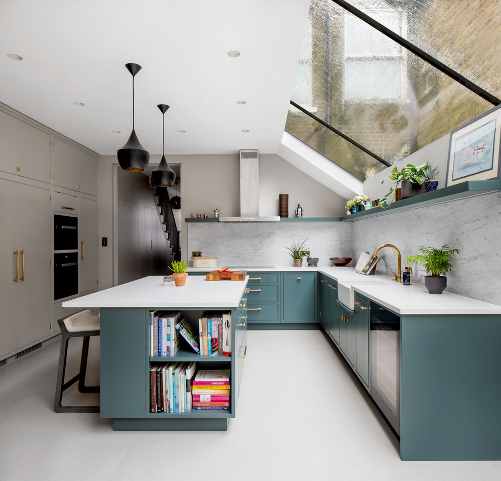Large contemporary u-shaped eat-in kitchen in London with a farmhouse sink, green cabinets, quartzite benchtops, marble splashback, stainless steel appliances, porcelain floors, with island, grey floor, white benchtop, flat-panel cabinets and grey splashback.