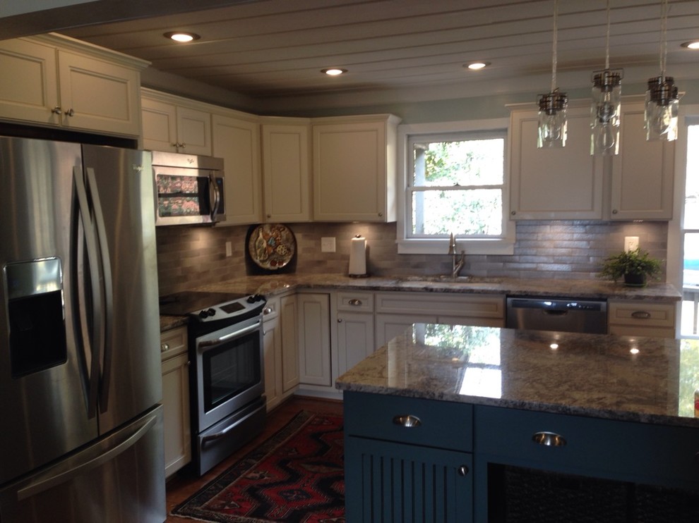 Example of a large transitional l-shaped medium tone wood floor kitchen pantry design with an island, flat-panel cabinets, beige cabinets, granite countertops, gray backsplash, porcelain backsplash, stainless steel appliances and an undermount sink