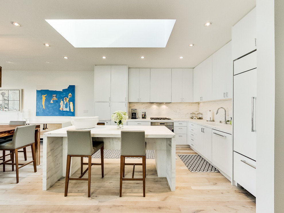 Inspiration for a contemporary l-shaped eat-in kitchen in San Francisco with an undermount sink, flat-panel cabinets, white cabinets, white splashback, white appliances, light hardwood floors and with island.