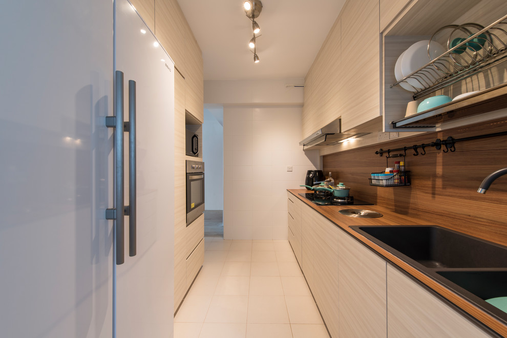 This is an example of a contemporary galley kitchen in Singapore with a double-bowl sink, flat-panel cabinets, light wood cabinets, brown splashback, white appliances, beige floor and brown benchtop.