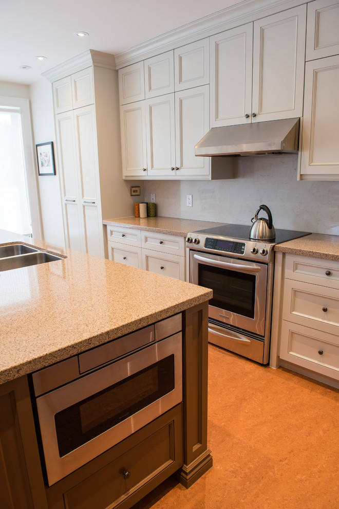 Photo of a large traditional l-shaped eat-in kitchen in Toronto with a double-bowl sink, recessed-panel cabinets, beige cabinets, limestone benchtops, white splashback, stone slab splashback, stainless steel appliances, cork floors and with island.