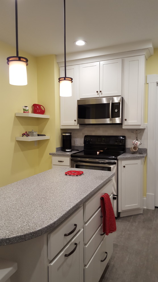 Example of a mid-sized transitional l-shaped vinyl floor enclosed kitchen design with an undermount sink, shaker cabinets, white cabinets, solid surface countertops, multicolored backsplash, stone tile backsplash, stainless steel appliances and an island