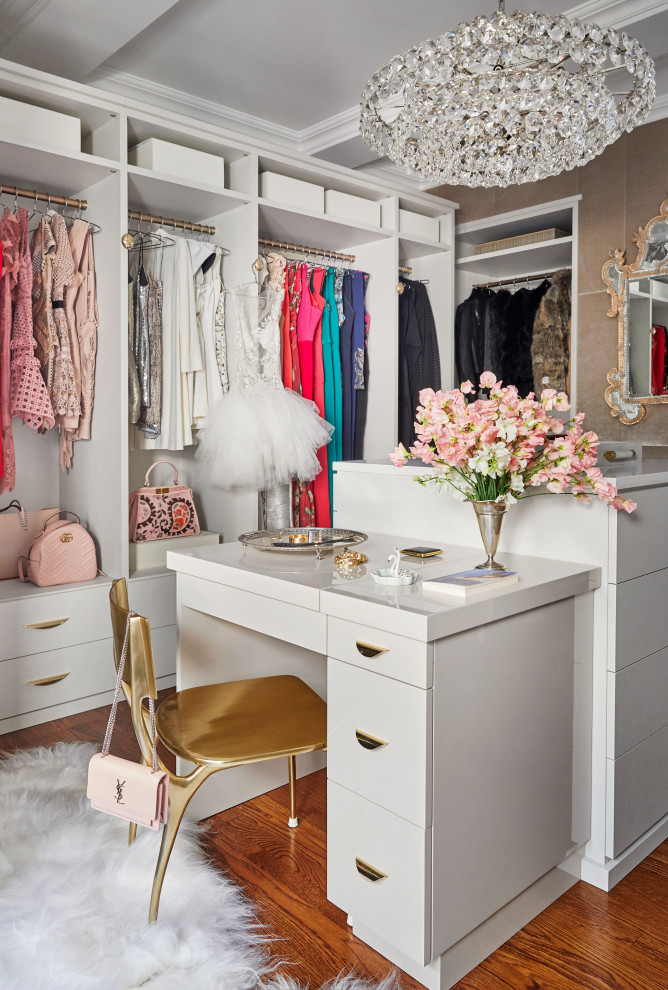 Contemporary women's dressing room in New York with open cabinets, white cabinets, medium hardwood floors and brown floor.