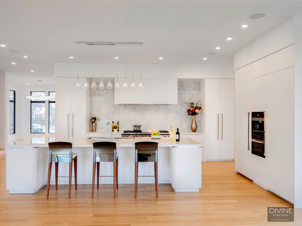 Example of a huge trendy brown floor kitchen design in Boston with white backsplash, paneled appliances, an island and white countertops
