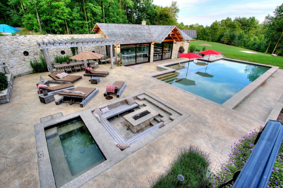 Design ideas for a large mediterranean front yard rectangular pool in Toronto with a hot tub and stamped concrete.