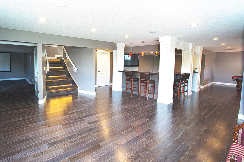 This is an example of a mid-sized modern walk-out basement in Other with beige walls, dark hardwood floors and brown floor.
