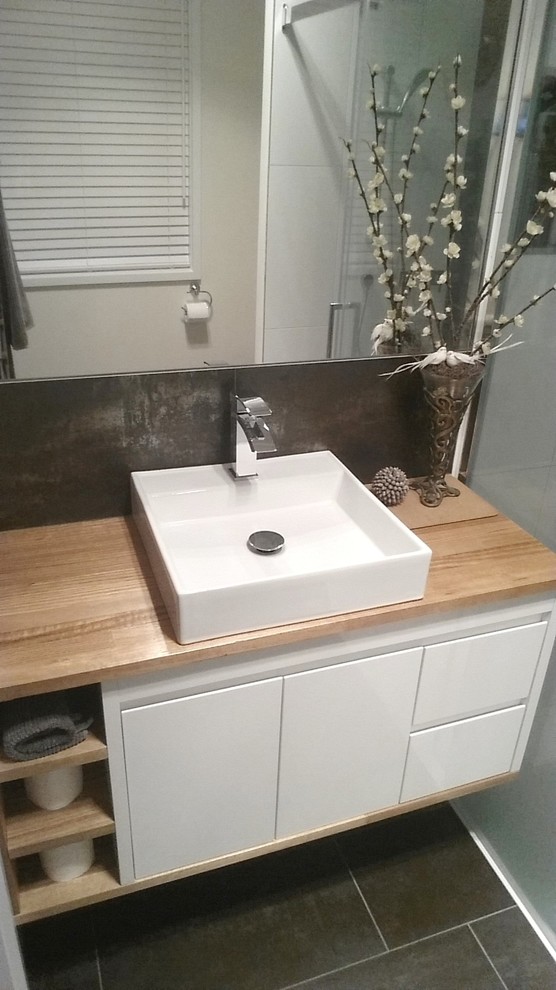 This is an example of a small contemporary master bathroom in Geelong with white cabinets, wood benchtops, gray tile, stone tile and beige walls.