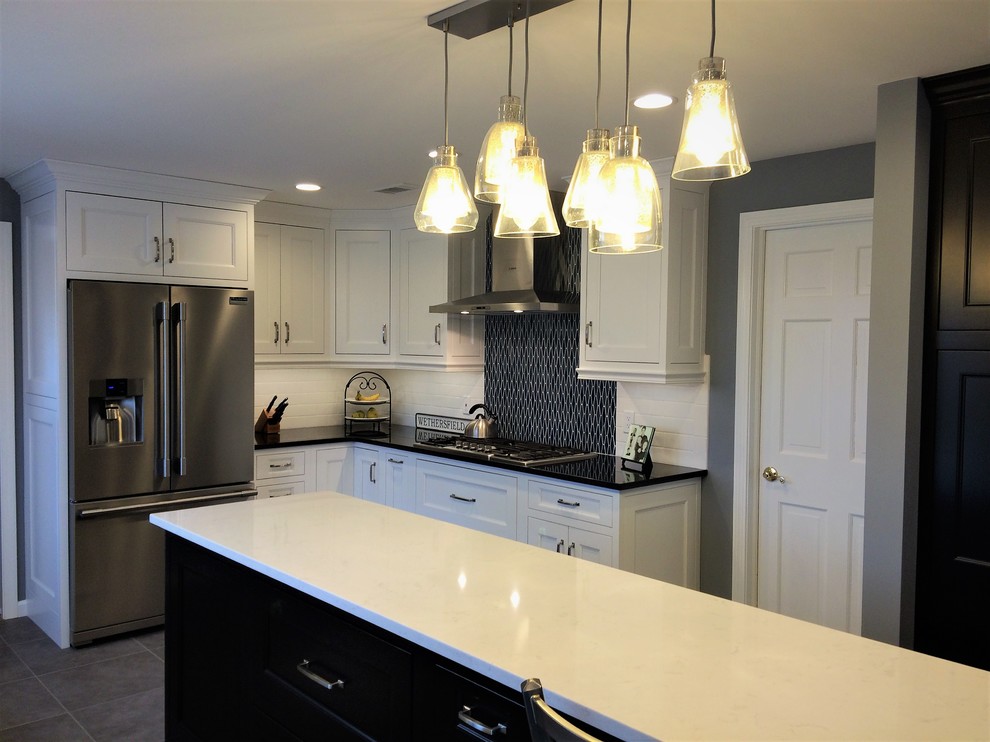 Large transitional galley porcelain tile and gray floor open concept kitchen photo with an undermount sink, recessed-panel cabinets, white cabinets, quartz countertops, blue backsplash, mosaic tile backsplash, stainless steel appliances, an island and black countertops