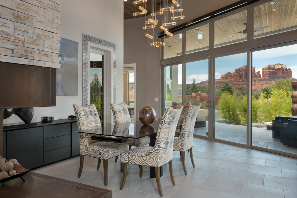 Photo of a large contemporary kitchen/dining combo in Phoenix with white walls, porcelain floors, a two-sided fireplace, a stone fireplace surround and beige floor.