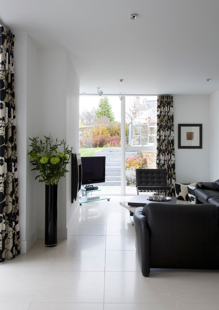 Mid-sized contemporary open concept living room in Edinburgh with white walls, ceramic floors, a standard fireplace, a freestanding tv and white floor.