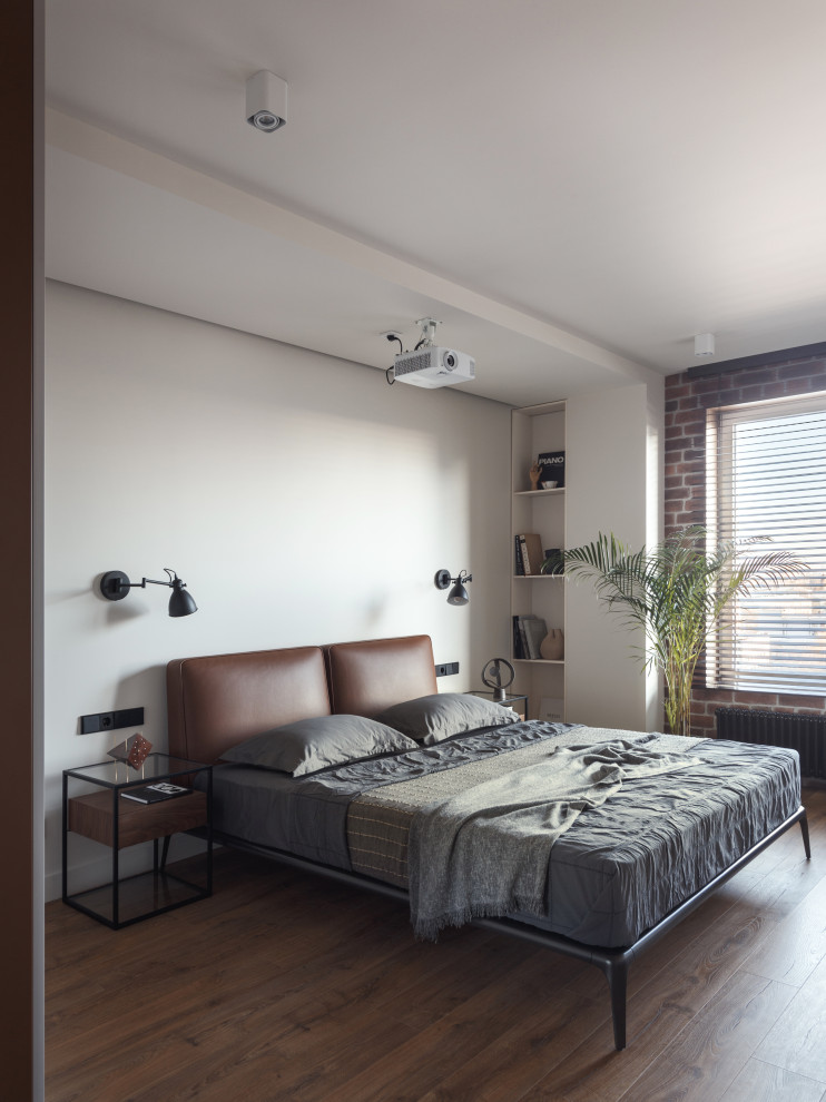 Photo of a medium sized industrial master and grey and white bedroom in Saint Petersburg with white walls, laminate floors, brown floors, a drop ceiling and brick walls.