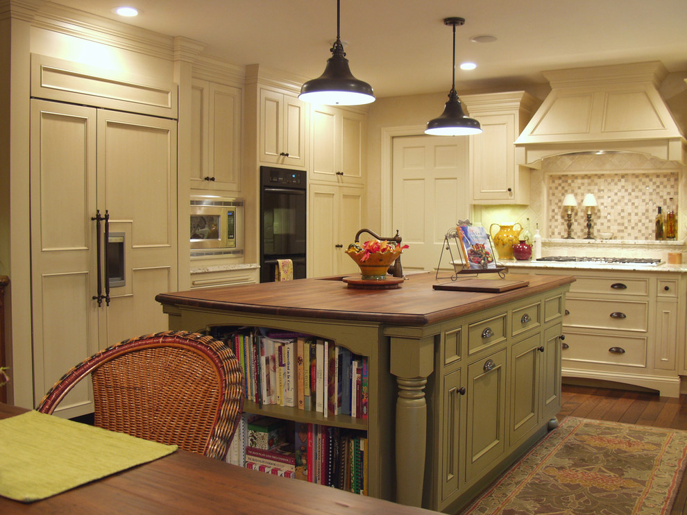 Traditional kitchen in Other with beaded inset cabinets, wood benchtops, panelled appliances and with island.