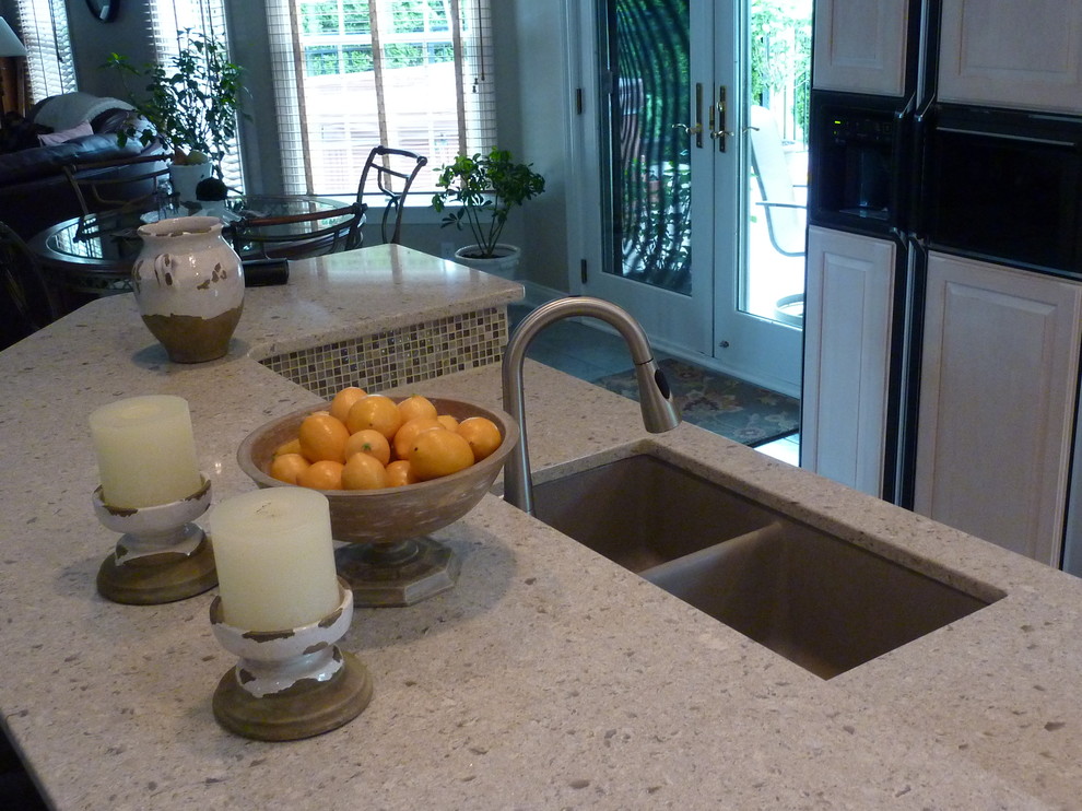 Example of a large transitional l-shaped ceramic tile eat-in kitchen design with an undermount sink, raised-panel cabinets, light wood cabinets, quartzite countertops, beige backsplash, glass tile backsplash, stainless steel appliances and an island