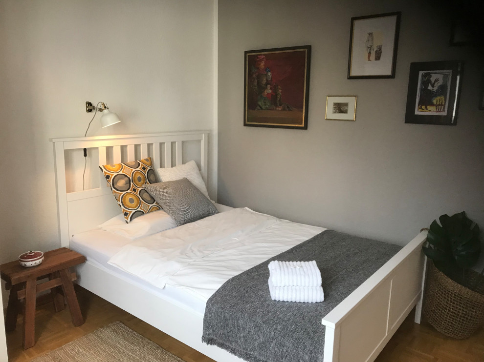 Kleines Skandinavisches Gästezimmer mit grauer Wandfarbe, gebeiztem Holzboden und beigem Boden in Köln