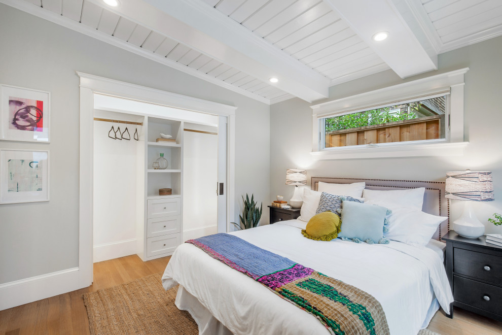 Ejemplo de dormitorio clásico renovado con paredes grises, vigas vistas y suelo de madera clara