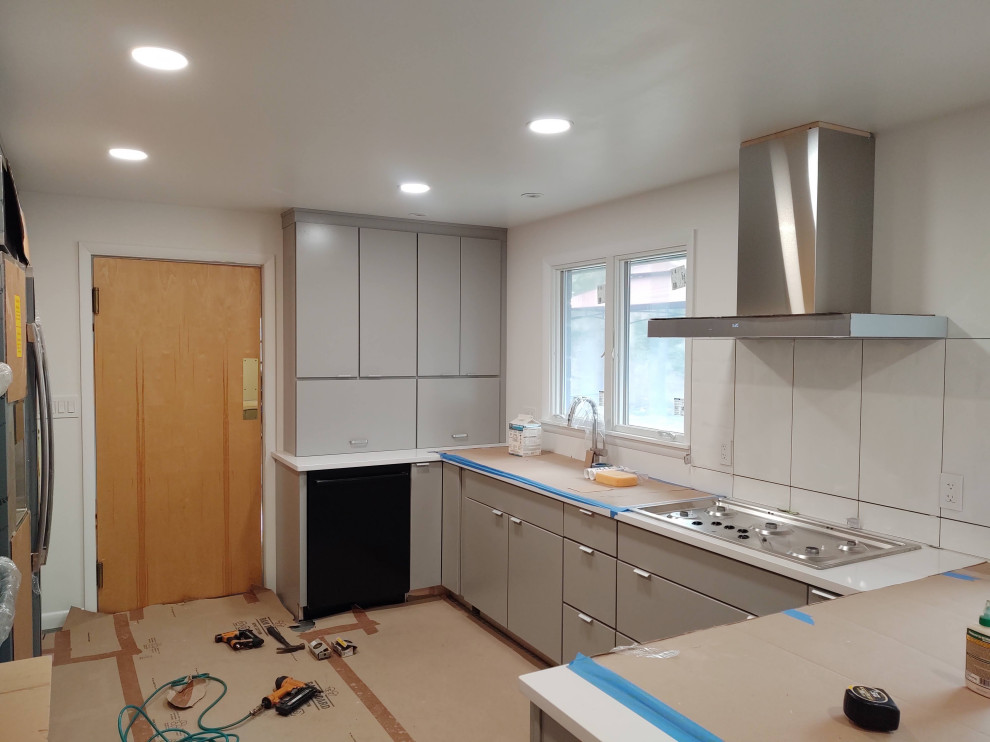 Example of a mid-sized enclosed kitchen design with flat-panel cabinets, gray cabinets and a peninsula