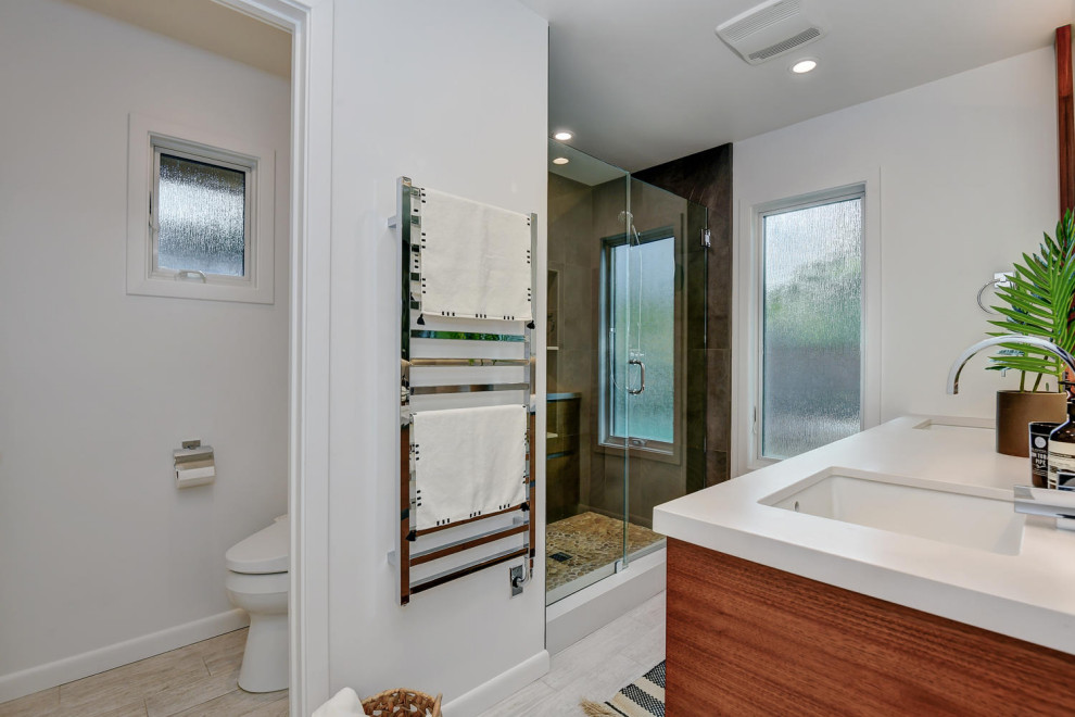 Photo of a mid-sized modern master bathroom in San Francisco with shaker cabinets, medium wood cabinets, a corner shower, a one-piece toilet, white tile, white walls, medium hardwood floors, an undermount sink, granite benchtops, brown floor, a hinged shower door and white benchtops.