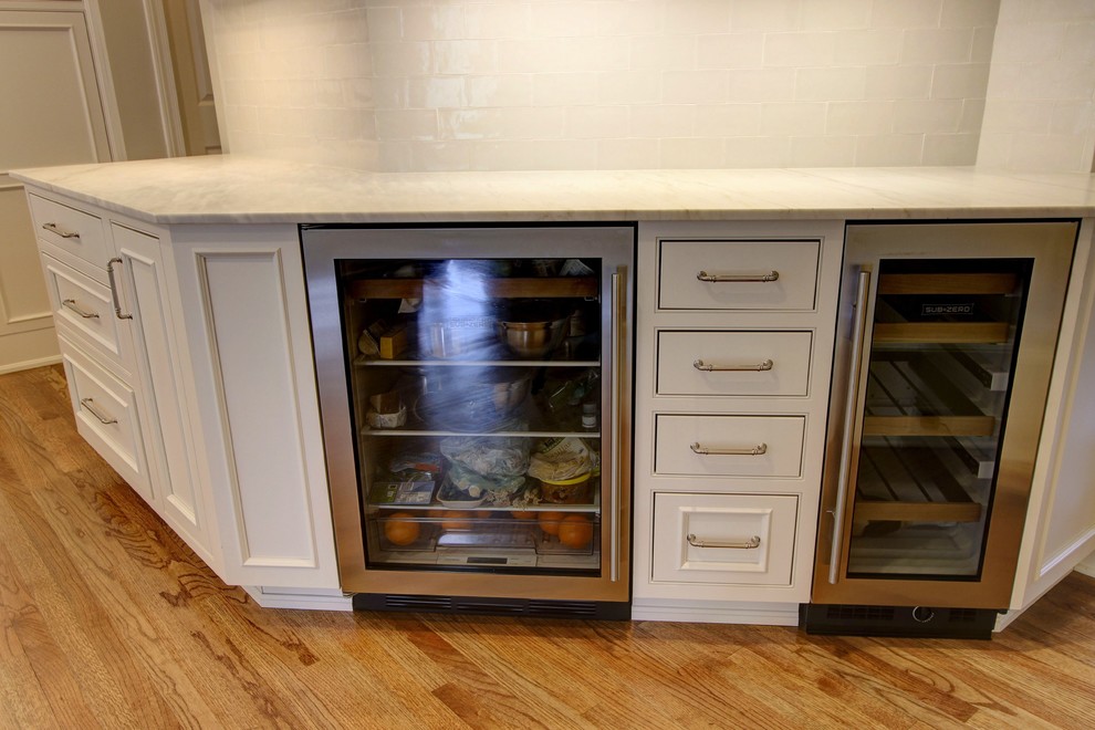 Large transitional u-shaped light wood floor kitchen pantry photo in Atlanta with an undermount sink, recessed-panel cabinets, white cabinets, quartz countertops, white backsplash, subway tile backsplash, stainless steel appliances and an island