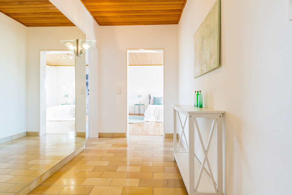 Photo of a mid-sized contemporary hallway in Other with white walls and beige floor.