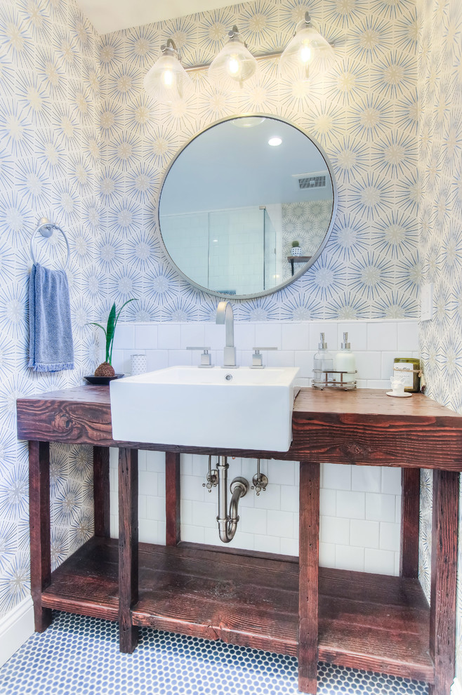 Photo of a mid-sized contemporary 3/4 bathroom in Los Angeles with open cabinets, a shower/bathtub combo, white tile, porcelain tile, multi-coloured walls, mosaic tile floors, wood benchtops, blue floor, a hinged shower door, dark wood cabinets, a drop-in sink and a one-piece toilet.