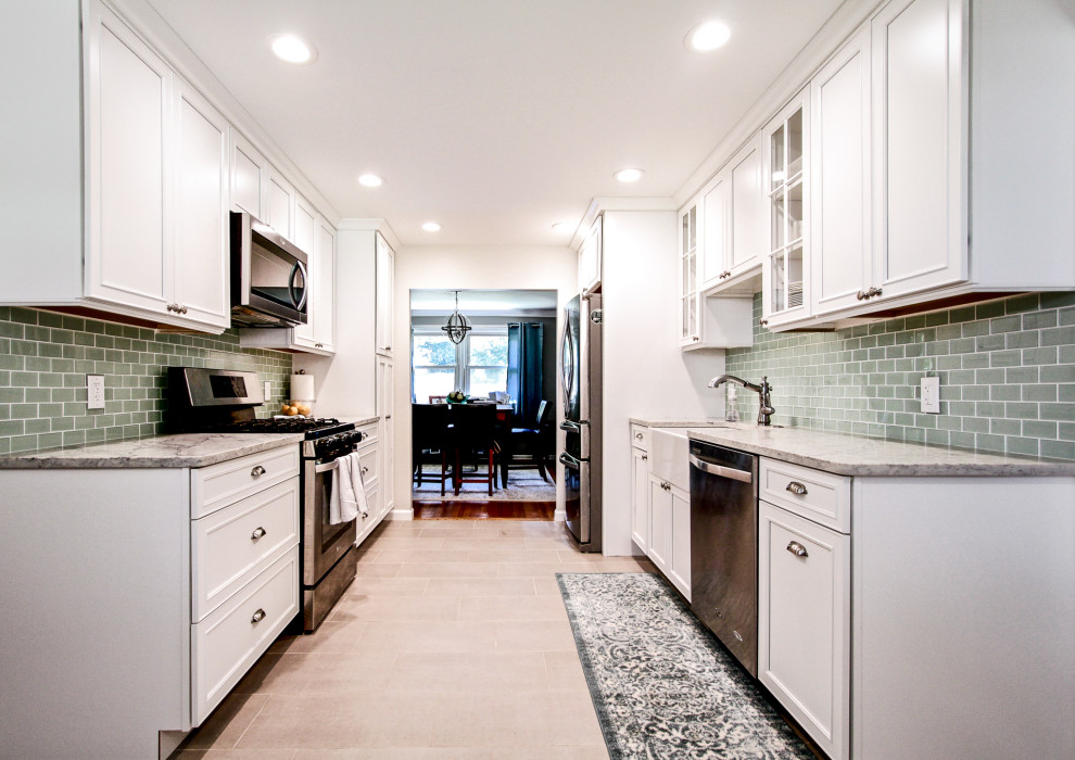 Large transitional galley eat-in kitchen in Philadelphia with a farmhouse sink, shaker cabinets, white cabinets, quartz benchtops, green splashback, glass tile splashback, stainless steel appliances, porcelain floors, no island, grey floor and multi-coloured benchtop.