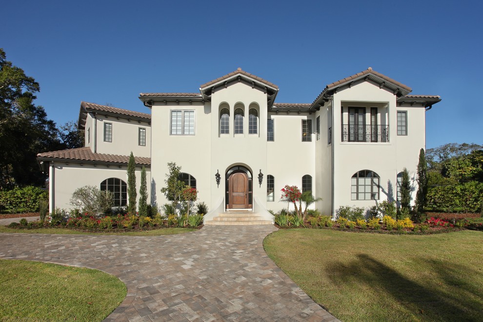Inspiration for a mid-sized mediterranean two-storey stucco white house exterior in Tampa with a gable roof and a tile roof.