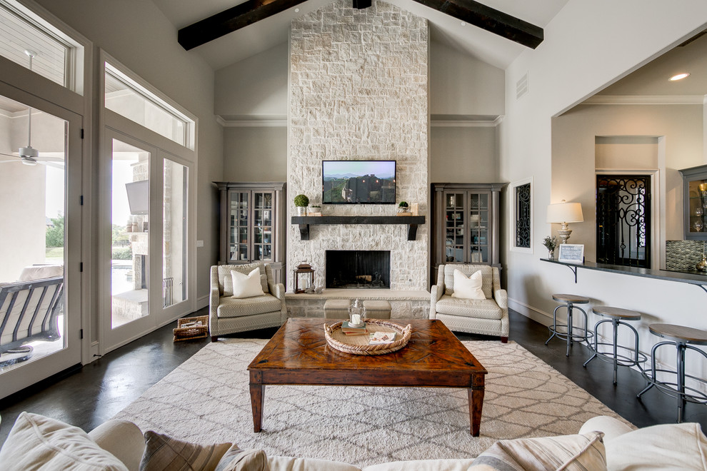 Inspiration for a large beach style open concept family room in Dallas with grey walls, dark hardwood floors, a standard fireplace, a stone fireplace surround and a wall-mounted tv.