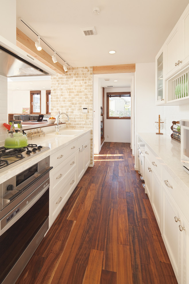Transitional galley separate kitchen in Other with recessed-panel cabinets, white cabinets, dark hardwood floors, brown floor, a drop-in sink, stainless steel appliances, no island and white benchtop.