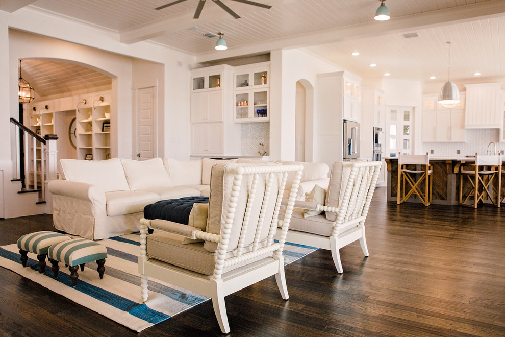 This is an example of a mid-sized beach style formal open concept living room in Dallas with white walls, dark hardwood floors, a ribbon fireplace, a wood fireplace surround, a concealed tv and brown floor.