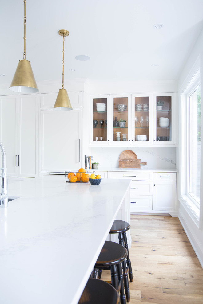Inspiration for a large contemporary l-shaped eat-in kitchen in Toronto with an undermount sink, shaker cabinets, white cabinets, quartz benchtops, white splashback, marble splashback, panelled appliances, medium hardwood floors, with island and brown floor.