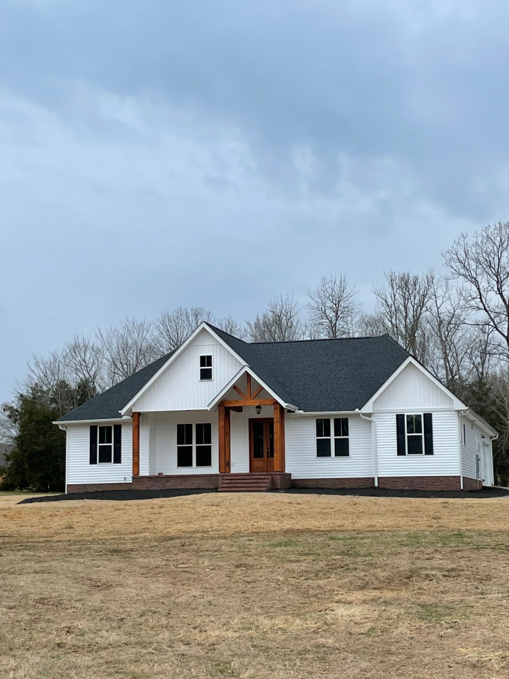 Cette image montre une façade de maison blanche rustique en bardage à clin de plain-pied avec un revêtement en vinyle, un toit en shingle et un toit noir.