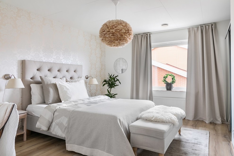 Scandinavian bedroom in Malmo with beige walls, medium hardwood floors and brown floor.