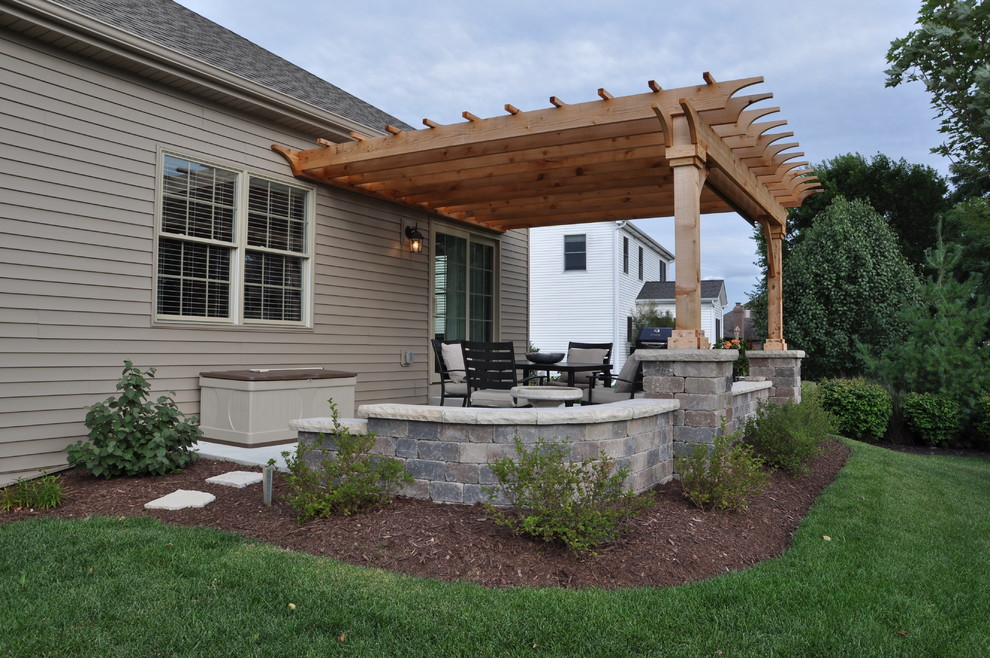 Photo of a mid-sized traditional backyard patio in Chicago with brick pavers and a pergola.