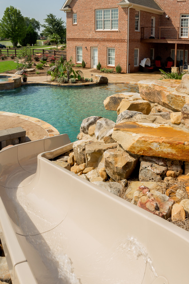 Photo of a country backyard custom-shaped natural pool in Atlanta with a water slide and stamped concrete.