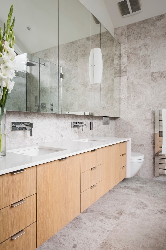 Mid-sized contemporary master bathroom in Vancouver with a wall-mount toilet, an undermount sink, flat-panel cabinets, medium wood cabinets, engineered quartz benchtops, a freestanding tub, a corner shower, gray tile, porcelain tile, grey walls, porcelain floors and white benchtops.