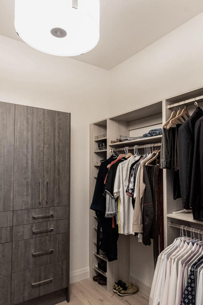 Photo of a mid-sized transitional gender-neutral storage and wardrobe in Calgary with open cabinets, dark wood cabinets, light hardwood floors and brown floor.