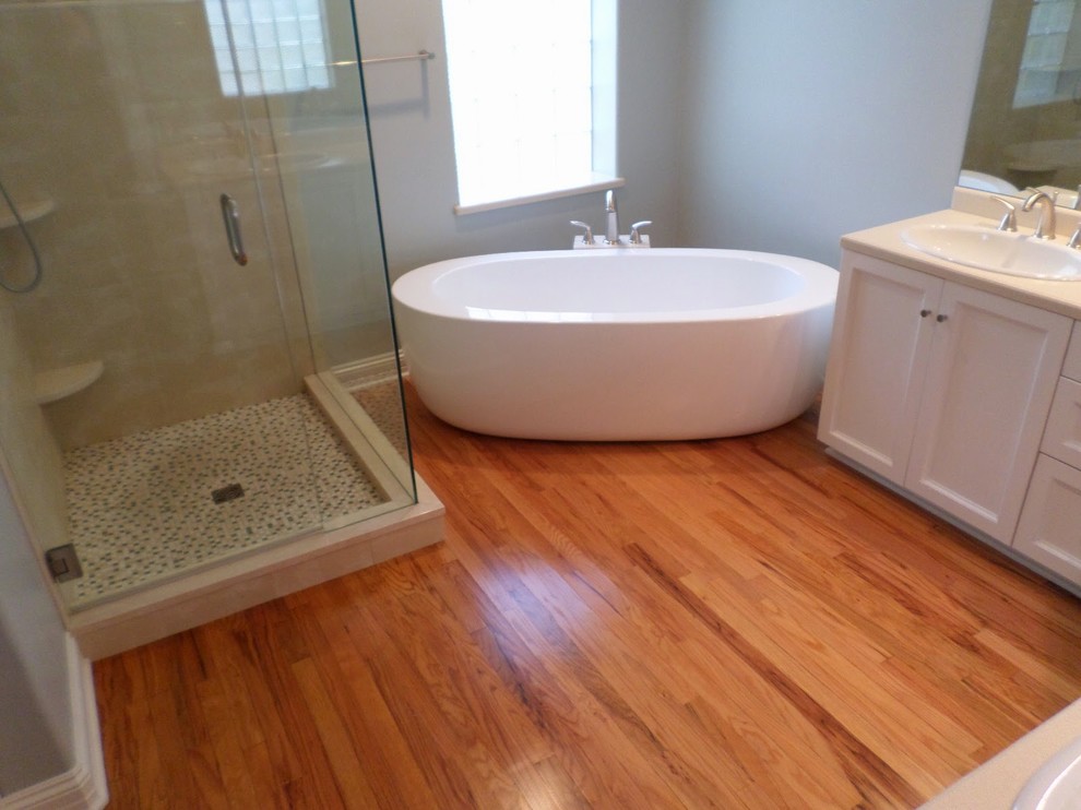 Small modern master bathroom in Denver with recessed-panel cabinets, white cabinets, limestone benchtops, a freestanding tub, a double shower, beige tile, porcelain tile, grey walls and light hardwood floors.