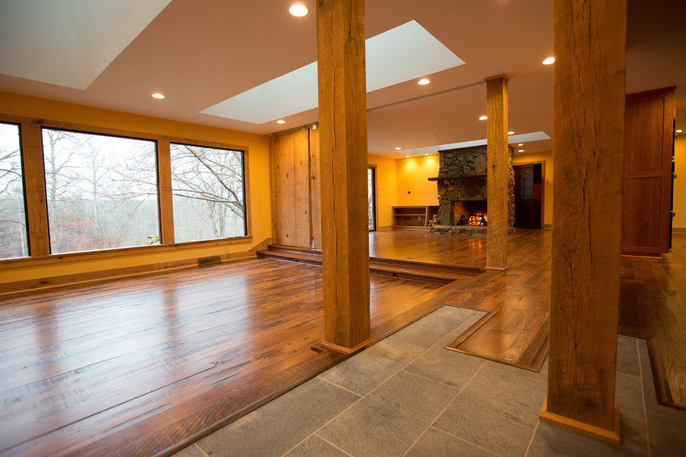 Large mountain style formal and open concept dark wood floor home design photo with orange walls, a standard fireplace, a stone fireplace and no tv