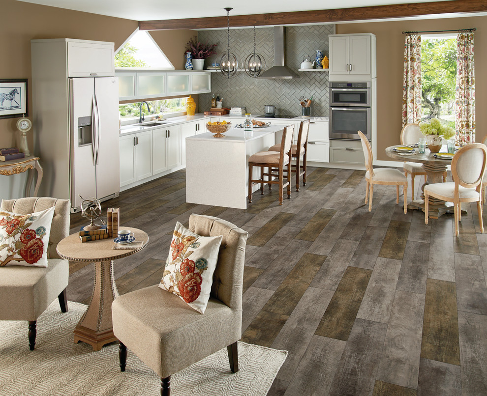 Mid-sized transitional l-shaped light wood floor and gray floor eat-in kitchen photo with an undermount sink, shaker cabinets, white cabinets, quartz countertops, gray backsplash, subway tile backsplash, white appliances and an island